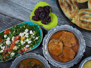 Eid Mubarak Traditional Ramadan Iftar dinner. Assorted tasty food in authentic rustic dishes on wooden table background.