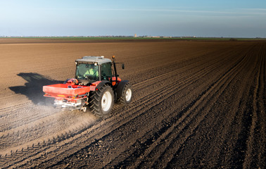 Obraz premium Tractor spreading artificial fertilizers in field