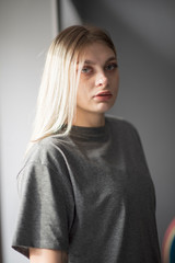 Portrait of a girl at the window in a gray t-shirt. Photographed close-up.