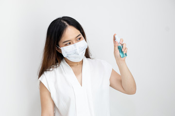 Close up of Asian girl wearing protective mask using alcohol antiseptic gel with copy space, isolated on white background. Concept of Coronavirus COVID-19, Coronavirus disease pandemic.