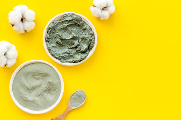Blue cosmetic clay - face and body skin care - on yellow background top-down copy space