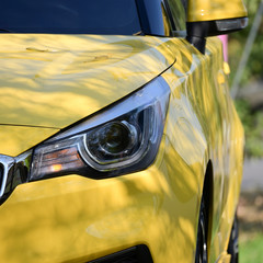 headlight of yellow modern car, image concept of summer road trip travel