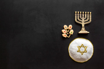 Fototapeta na wymiar Jewish Kippah Yarmulkes hats with menorah on black wooden table. Top view, copy space