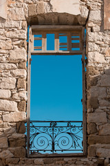 wall with window with wooden frame and rusty wrought iron fence on the bottom close up, light brown brick wall building