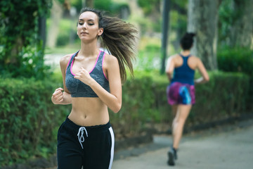 Young girl running in the park. Sportive woman playing fitness outdoor. Sport, wellness and healthy living lifestyle concept.