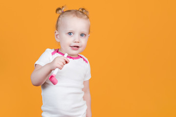 Little girl with a festive whistle on an orange-yellow background