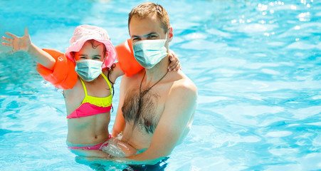 Young cheerful father and his little daughter in a swimming pool