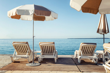 Sunbeds with umbrellas on the pier against the backdrop of the sea. Resort in the south of France....