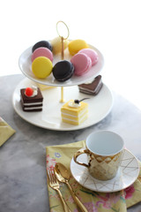 afternoon tea with a colorful macarons and cakes on level cake stand