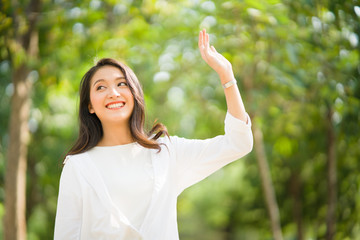 Portrait shot of happy, successful, attractive bearded  of Asian woman with big smiling with a confident look toward the camera at a blur park background with copy space in natural sunlight.