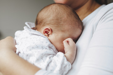 newborn in the arms of the mother who hides her face with her hand