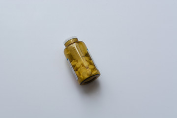Orange transparent packaging with white pills on a uniform light gray background with a slight shadow