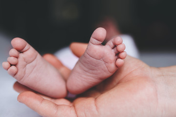 close up of a mother's hand holding her baby's feet