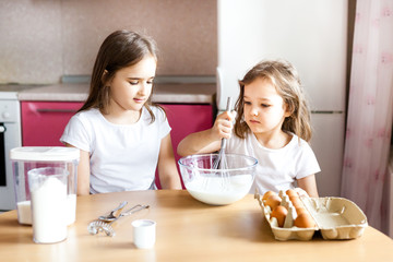 Obraz na płótnie Canvas Sisters prepare Breakfast, pastries, mix flour, milk, eggs, pancakes in a bowl, children help mother, family Breakfast, cooking