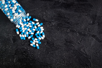 Creatine capsules. Pills scattered on black background top view copy space