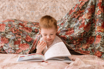 a boy plays with a book at home. The concept of home time.