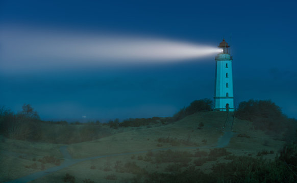 The Dornbusch lighthouse on the German Baltic island of Hiddensee at night. It was a bright winter night by moonlight. There is some fog in the air. That's why you see the light beam very well.