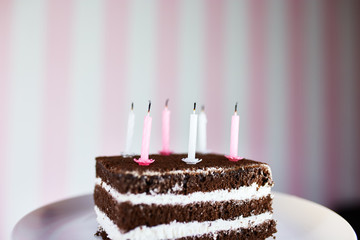 Birthday cake with burning candles on color pink background.