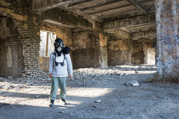 The child in the gas mask  on the abandoned, destroyed brick building.Environment pollution.Apocalypse postnuclear Doomsday scenario.