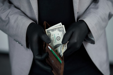 Man holding a wallet with  money dollars  in hand in black medical gloves. Coronavirus crisis. Save money. No maney.  The world crisis