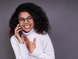 Laughing dark-skinned young girl speaks on the phone.