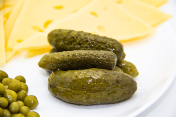 Beautiful cucumbers and green peas and sliced ​​cheese on white plate  against background. Keto diet with very healthy and tasty meal for luch