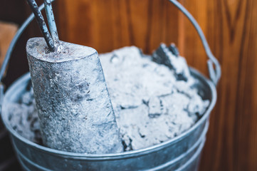 Charcoal and ash are cleaned from the home fireplace in an iron galvanized bucket.