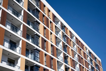 Fototapeta premium Exterior of new apartment buildings on a blue cloudy sky background. No people. Real estate business concept.