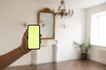 Man at Home Lying on a Couch using Smartphone with Green Mock-up Screen, Doing Swiping. Guy Using...
