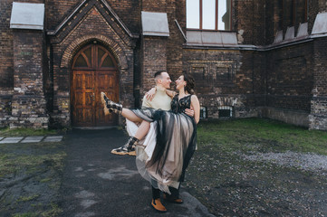 The loving groom holds in his hands a lovely bride in an expensive dress and chuny against the...