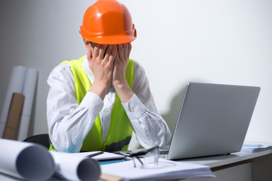 Crisis concept. An unemployed man is sad while sitting at his workplace. Depressive state, stress at the engineer in a helmet.
