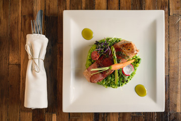 Grilled chicken breast fillet wrapped in bacon served with green risotto on a white plate shot from...
