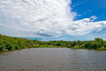 Summer warm day near the river with clouds in the sky