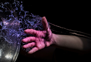 Female hand on which a drop of water falls on a black background