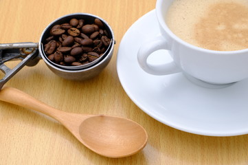 Coffee cup and beans on wooden kitchen table. Top view with morning sunlight
