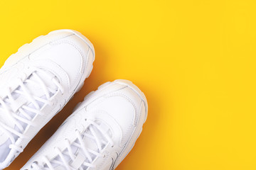 White sneakers on vivid yellow background. Sport, running, workout concept. Flatlay, top view. Copy space for your text.