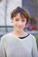 Closeup view of cheerful young lady on street. Beautiful smiling young woman looking at camera. Female beauty concept