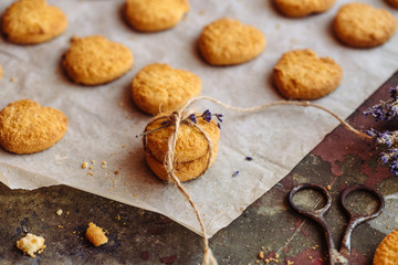 Fototapeta na wymiar Freshly baked heart-shaped cookies on parchment paper, lavender flower