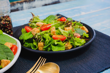 Couple bowl of healthy green vegetable salad on top with tomatos and biscuits. Side dish with salt pepper bottle, white cream and thousand island salad dressing