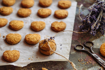 Freshly baked heart-shaped cookies on parchment paper, lavender flower