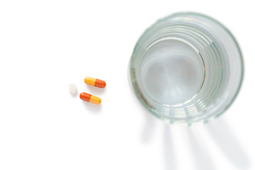 Glass and pills isolated on white background