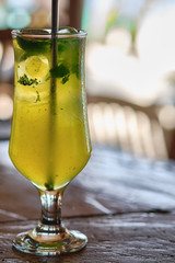 Yellow beach cocktail with a straw on the background of a sandy beach.