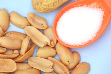 Top view peanuts with salt on spoon on white background, selective focus