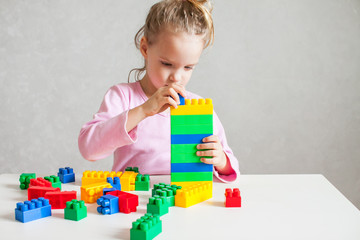 little girl plays with multi-colored plastic constructor