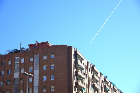 Abitazioni nel centro di Barcellona con la scia di un' aereo nel cielo azzurro, Spagna.