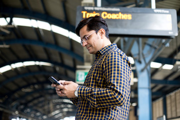 Man using mobile phone at railroad station platform