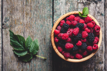 raspberries and blackberries on a wooden background in vintage style. Cutting board