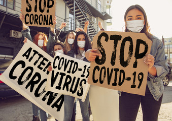 Young people protesting of stop coronavirus pandemic on the street. Caucasian women have meeting about problem in medicine, healthcare system, danger epidemic. Copyspace. Stop coronavirus, COVID-19.
