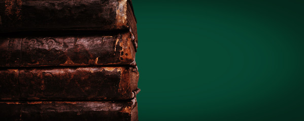 Stack of old worn leather covered books on malachite color background. Banner. Copy space.