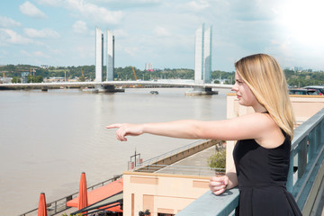 charming young blonde tourist woman on Bordeaux quay in france Garonne riverside pointing river finger